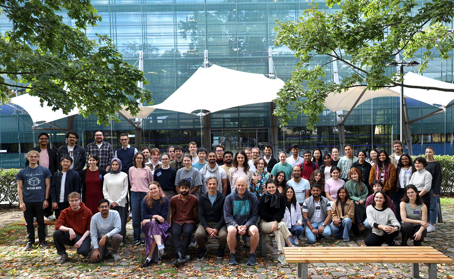 group shot in front of the institute entrance with all participants, blue green background