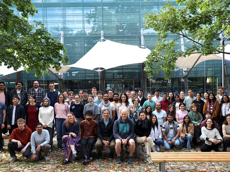 group shot in front of the institute entrance with all participants, blue green background